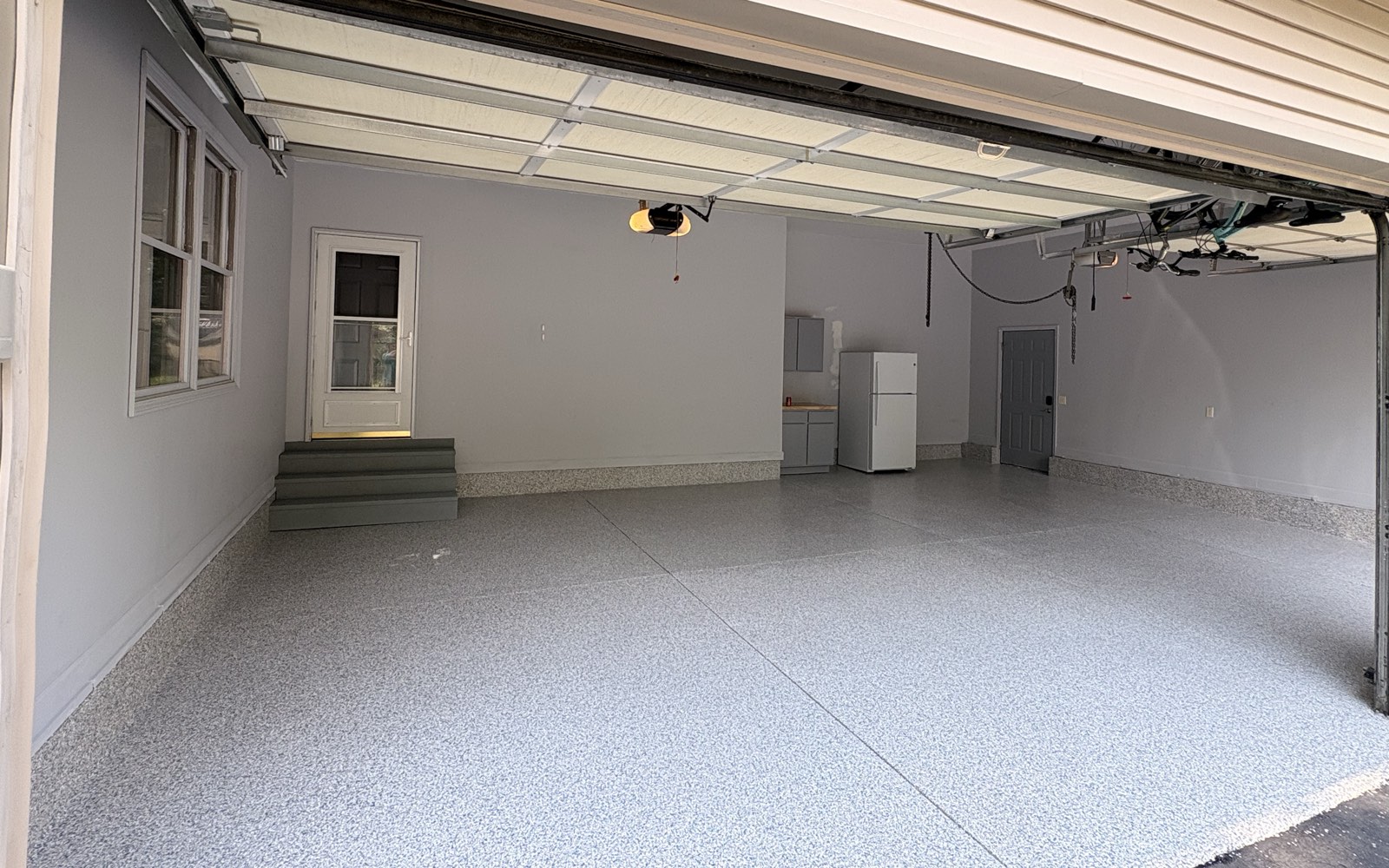 The same Tipton garage after: a grey and blue flake epoxy floor sealed under a clear polyaspartic topcoat.